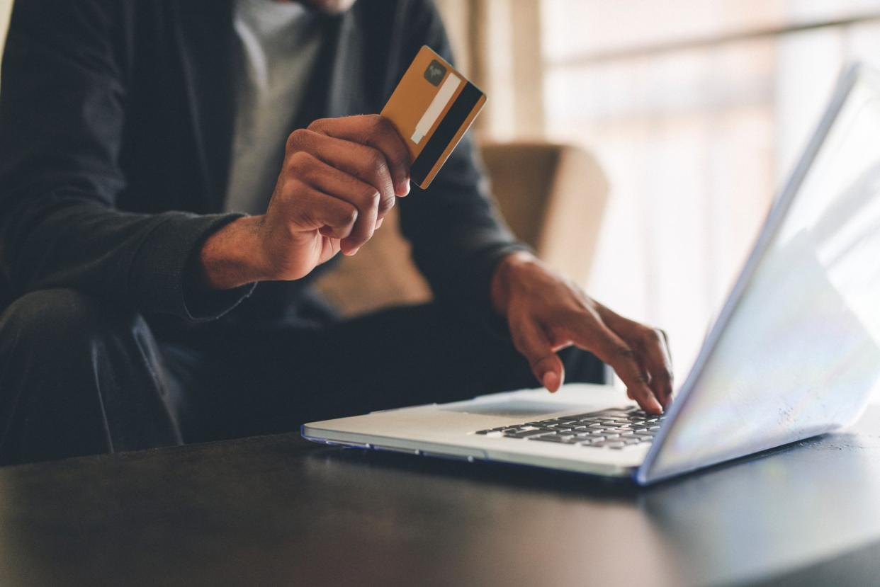 Cropped shot of an unrecognizable man using a credit card and a laptop to shop online at home.