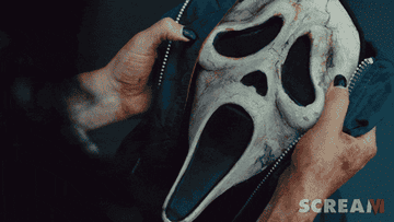 A woman examines a tattered ghostface mask
