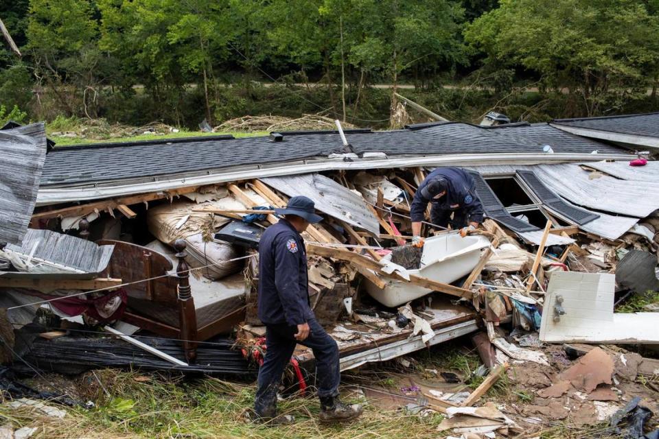 Members of the Lexington Fire Department look through the wreckage of a home while operating as search and rescue units along KY-476 along Troublesome Creek in Breathitt County, Ky., Sunday, July 31, 2022.