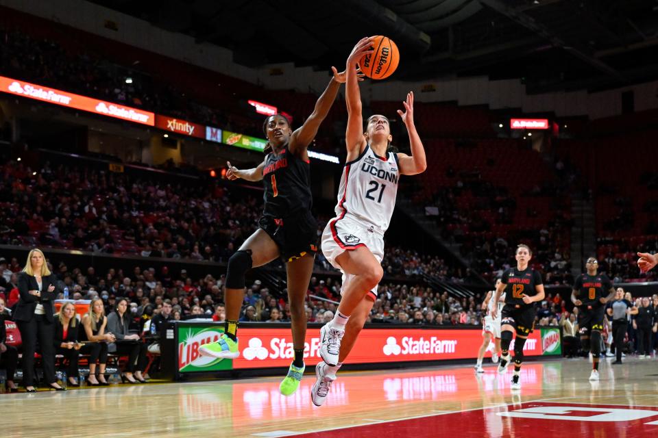 Connecticut guard Ines Bettencourt (21) goes to the basket for a lay up and avoids defender Maryland guard Diamond Miller (1) during the first half of an NCAA college basketball game, Sunday, Dec. 11, 2022, in College Park, Md. (AP Photo/Terrance Williams)