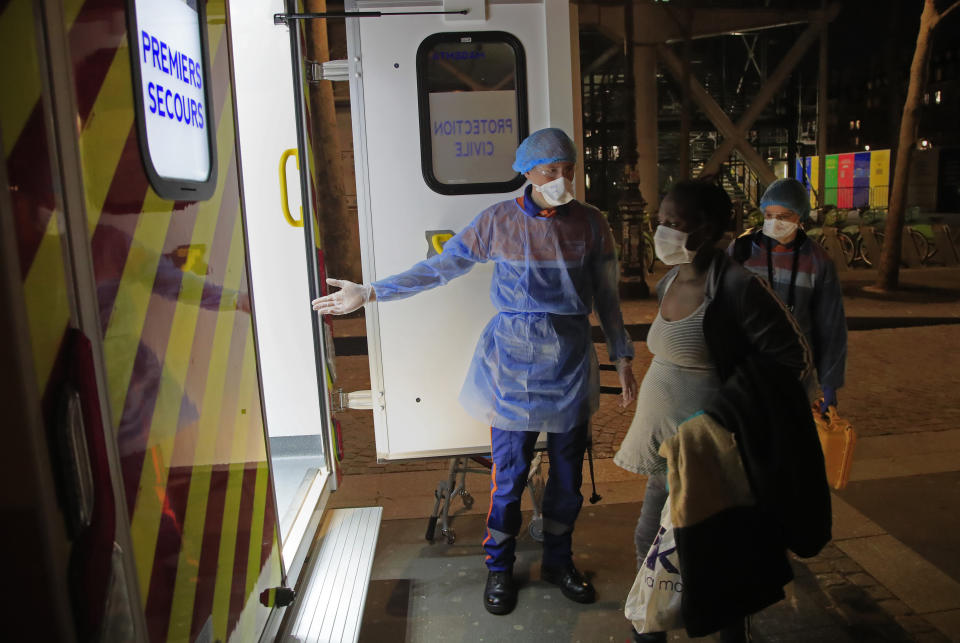 In this photo taken Thursday, March 26, 2020, members of the Civil Protection service, Vincent Jactel, left, and Aurore Lejeune, right, escort a 27-year-old pregnant woman suspected of being infected with the Covid-19 virus in Paris. They don't have to put themselves in harm's way, but the volunteers of France's well-known Civil Protection service choose the front line in the fight against the coronavirus. (AP Photo/Michel Euler)