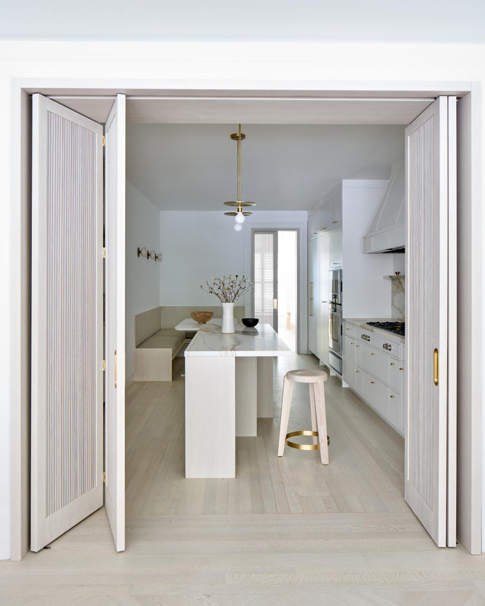 Minimalist white kitchen featuring stepped kitchen island with cantilevered countertop