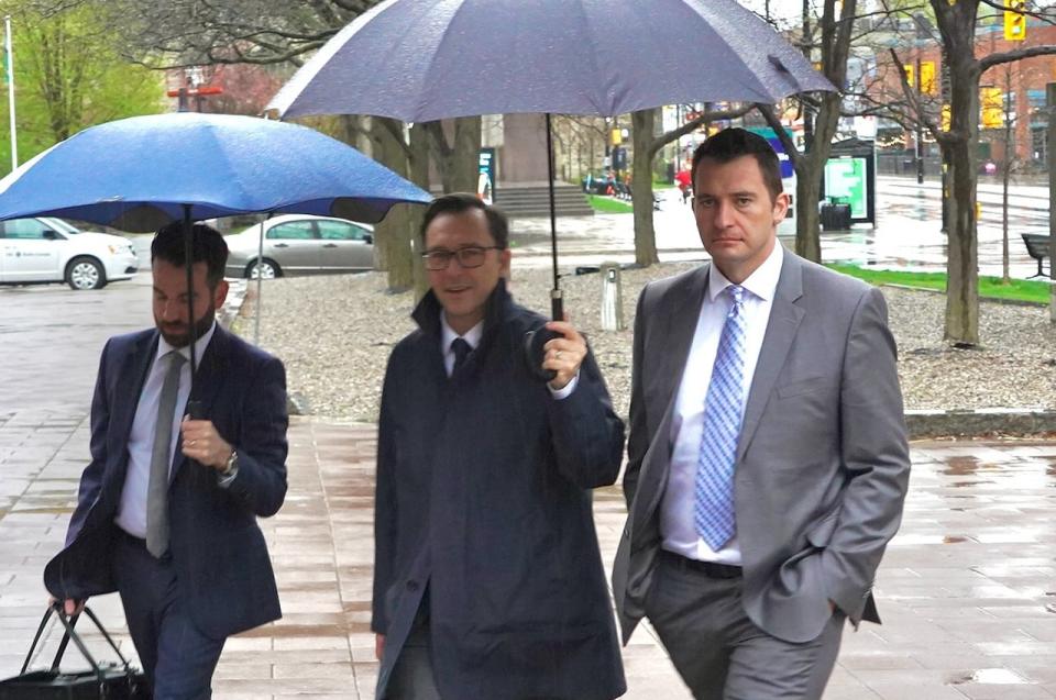 Former firefighter Eric Einagel, at far right, walks with members of his legal team outside the Ottawa Courthouse on May 8, 2024.