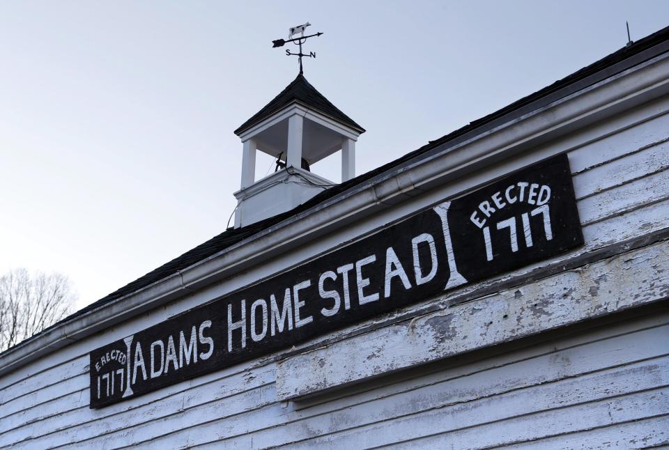 Une pancarte sur une remise à claques blanche indique Adams Homestead, Erected 1717