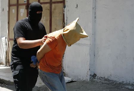 A Hamas militant grabs a Palestinian suspected of collaborating with Israel, before being executed in Gaza City August 22, 2014. Hamas militants killed seven Palestinians suspected of collaborating with Israel in a public execution in a central Gaza square on Friday, witnesses and a Hamas website said. REUTERS/Stringer