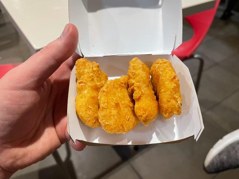 hand holding a box of four chicken nuggets from mcdonalds