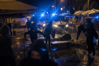 Demonstrators throw objects towards police during a protest condemning the arrest of rap singer Pablo Hasel in Barcelona, Spain, Friday, Feb. 19, 2021. The imprisonment of Pablo Hasel for inciting terrorism and refusing to pay a fine after having insulted the country's monarch has triggered a social debate and street protests. (AP Photo/Felipe Dana)