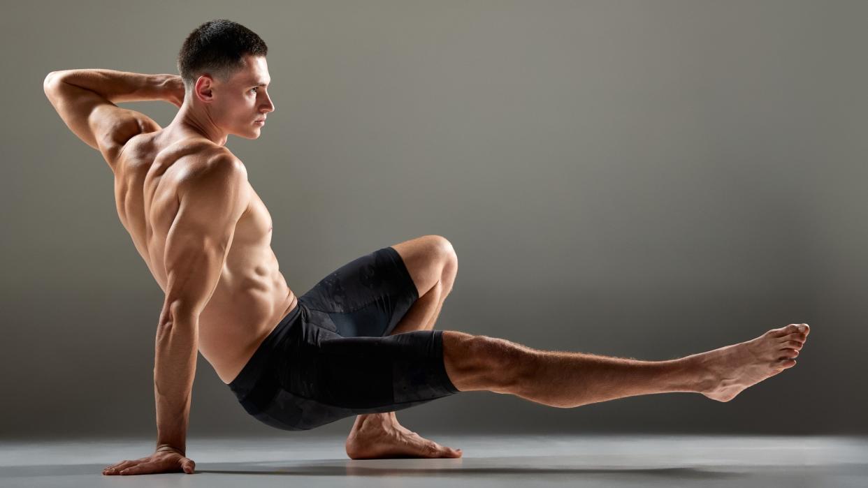  Male muscular athlete showing animal flow sport elements isolated over grey background. 