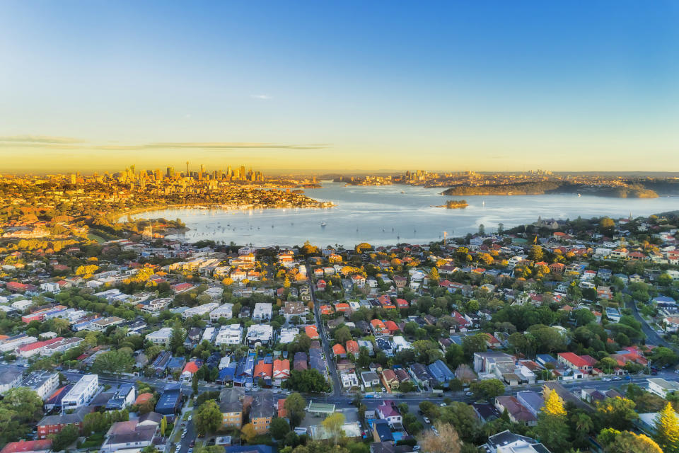 Wealthy Eastern suburbs of Sydney city around Harbour in aerial view with soft morning light and blue sky.