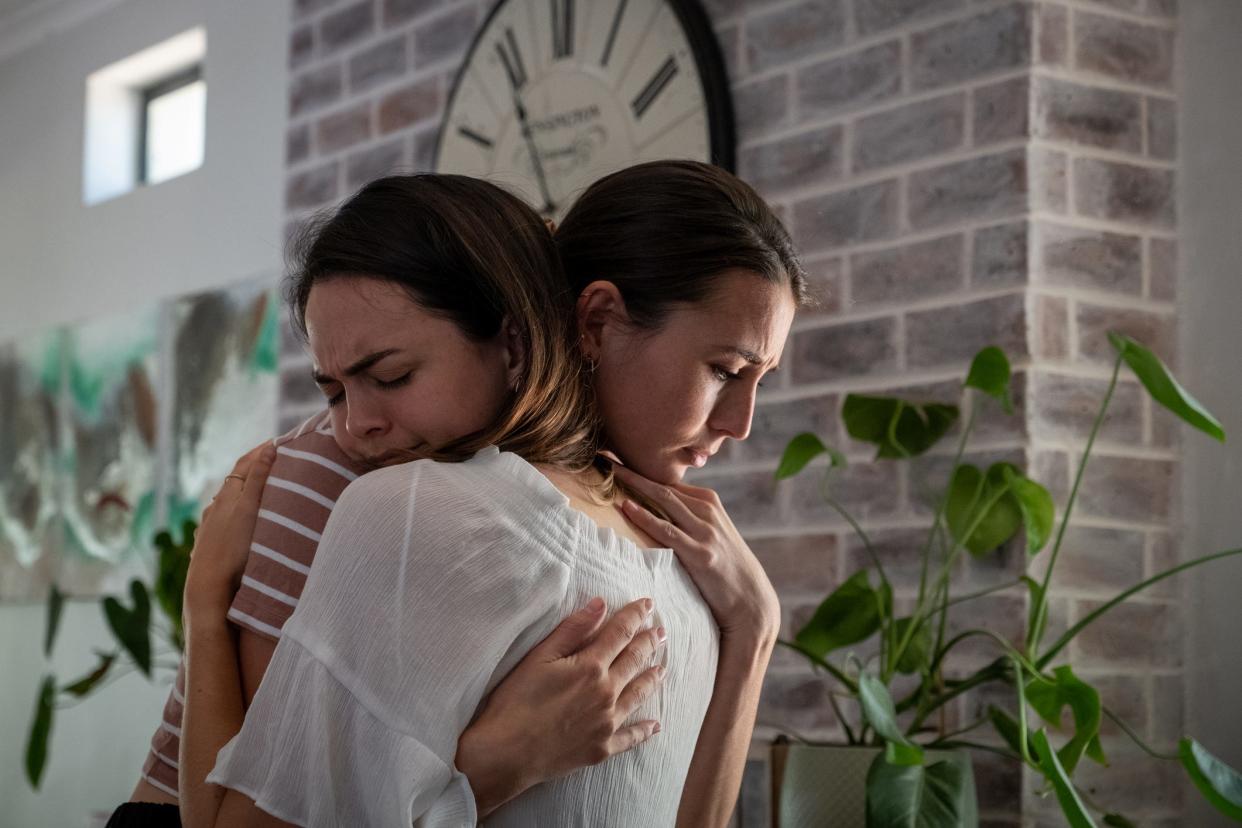 A woman comforts her friend with a hug.