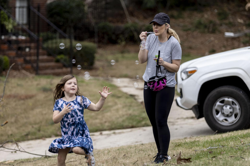 Kelsey Manley bows bubbles for her daughter Marin, 5, on Eagle Point Drive in Birmingham, Ala. to help each other decompress after their home was impacted by a tornado the previous day, Friday, March 26, 2021. (AP Photo/Vasha Hunt)