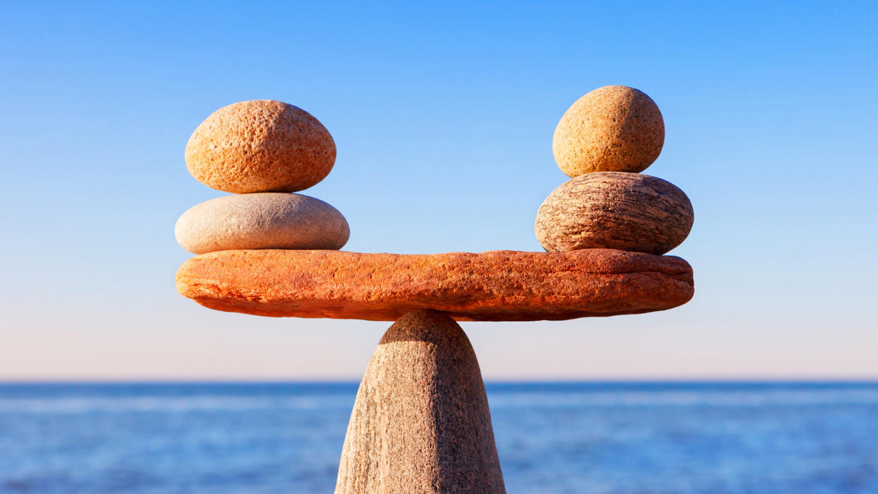 Symbolic scale of the stones on sea background closeup.