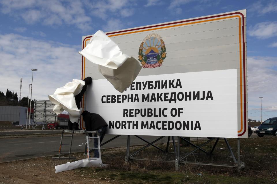 Workers replace signage with an adhesive banner that reads Republic of North Macedonia in the southern border with Greece, near Gevgelija, Wednesday, Feb. 13, 2019. Workers in the newly renamed North Macedonia have begun replacing road signs to reflect the change in their country's name, following a deal with neighboring Greece to end a nearly three decade-long dispute and secure NATO membership. (AP Photo/Boris Grdanoski)