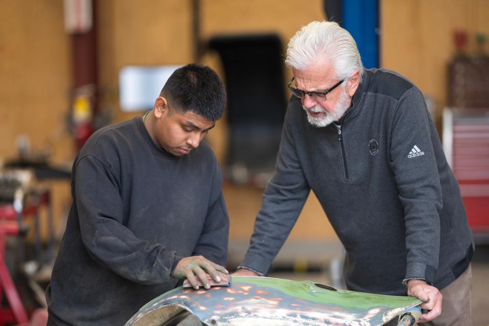 Instructor Tom Forgette supervises Abel Galindo, a student in the auto and diesel repair and car restoration program at Rancho Cielo, as he sands a dent out of a fender.
