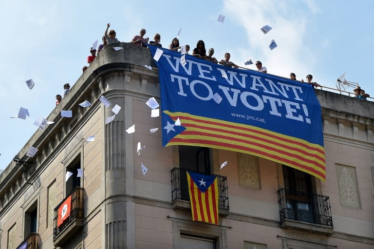 A group of people in Barcelona throw ballots for the October 1 referendum from a building with a banner in favour of the referendum, with Spain's prime minister asking Catalan leaders to admit their plans have been dealt a serious blow