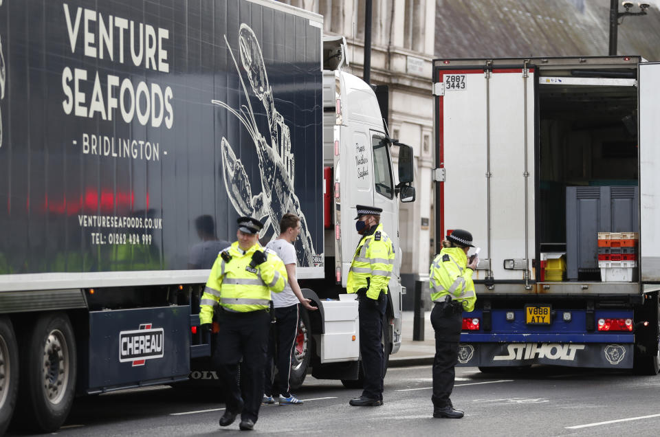 Police speak to shellfish export truck drivers as they are stopped for an unnecessary journey in London, Monday, Jan. 18, 2021, during a demonstration by British Shellfish exporters to protest Brexit-related red tape they claim is suffocating their business. The drivers were later stopped by police and issued with fines for an 'unnecessary journey' due to the national lockdown to curb the spread of the coronavirus. (AP Photo/Alastair Grant)