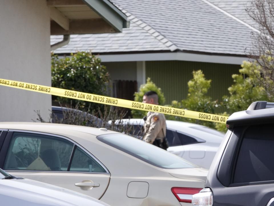A Ventura County Sheriff's deputy visible behind police tape walks toward the site of a fatal shooting at a home on Sandra Court in Newbury Park on Feb. 17.