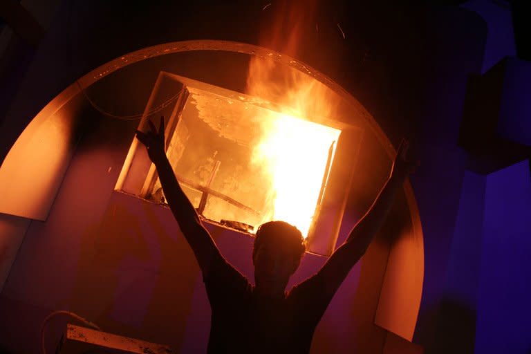 A Libyan demonstrator flashes the victory sign near the burning headquarters of the hardline Islamist group Ansar el-Sharia on September 21, 2012 in Benghazi. Security has proven the biggest challenge facing the government since the ouster of Libyan dictator Moamer Kadhafi last year