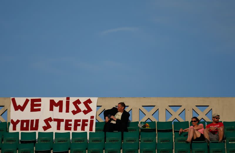 A man sits on the tribune next to a banner refeering to former German tennis player Steffi Graf during a match at the French Open Tennis tournament at the Roland Garros stadium in Paris