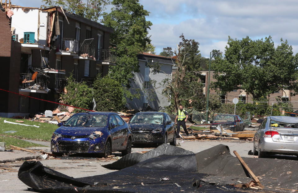 <p>A police officer walks past damaged cars and apartment buildings in a Gatineau, Que. neighbourhood on Saturday, September 22, 2018. A tornado on Friday afternoon tore roofs off of homes, overturned cars and felled power lines in the Ottawa community of Dunrobin and in Gatineau, Que. (Photo from Fred Chartrand/The Canadian Press) </p>