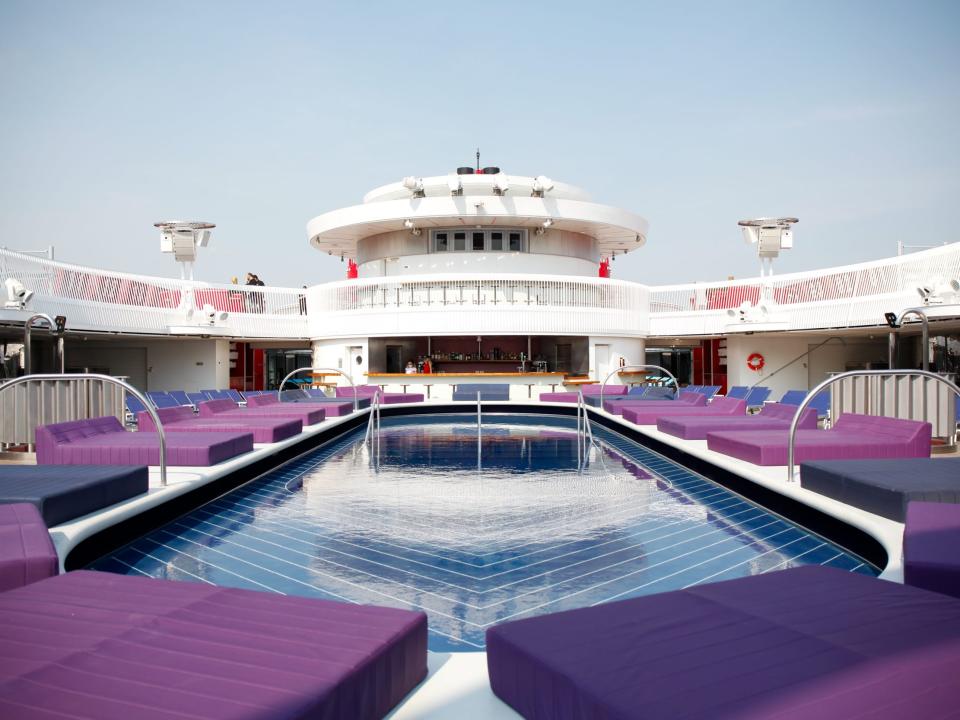 a pool on an outdoor deck surrounded by beds and chairs