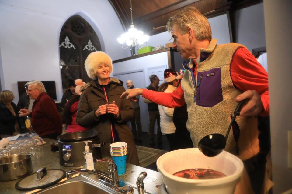 Saint Margaret's Episcopal Church pastor Michael Corrigan stirs mulled wine as he chats with Sarah Miller after a night of singing Christmas carols in Staatsburg on December 14, 2022.