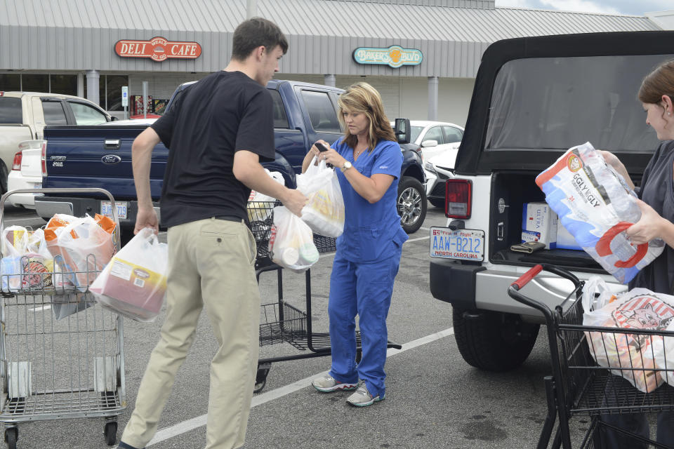 From left, Douglas Hill loads groceries into Wendy Cannon's jeep as she and Logan Coombs, right, purchased items from the Piggly Wiggly in preparation for Hurricane Florence in Kinston, North Carolina, on Monday.