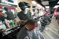 Wallace Wilson, top, cuts the hair of James McRae, Friday, April 9, 2021, in Hyattsville, Md. Wilson is a member of the Health Advocates In Reach & Research (HAIR) program, which helps barbers and hair stylists to get certified to talk to community members about health. During the COVID-19 pandemic, a team of certified barbers have been providing factual information to customers about vaccines, a topic that historically has not been trusted by members of black communities because of the health abuse the race has endured over the years. (AP Photo/Julio Cortez)