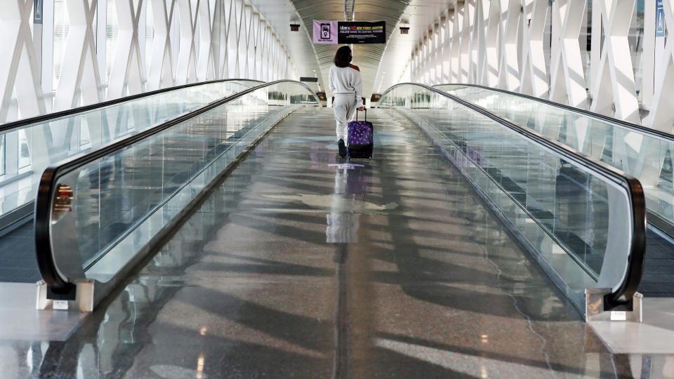 A traveler walks with her luggage across a nearly empty skyway bridge at Logan Airport, Friday Nov. 20, 2020, in Boston. With the coronavirus surging out of control, the nation's top public health agency pleaded with Americans not to travel for Thanksgiving and not to spend the holiday with people from outside their household. (AP Photo/Michael Dwyer)