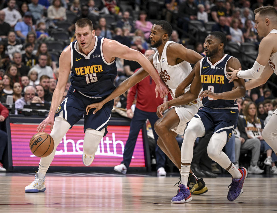 DENVER, CO - MARCH 31: Nikola Jokic (15) of the Denver Nuggets drives past Evan Mobley (4) of the Cleveland Cavaliers as Justin Holiday (9) runs interference during the first quarter at Ball Arena in Denver on Sunday, March 31, 2024. (Photo by AAron Ontiveroz/The Denver Post)