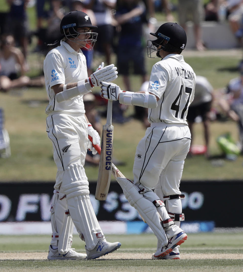 New Zealand's Mitchell Santner, left, is congratulated by teammate BJ Watling after scoring a century during play on day four of the first cricket test between England and New Zealand at Bay Oval in Mount Maunganui, New Zealand, Sunday, Nov. 24, 2019. (AP Photo/Mark Baker)