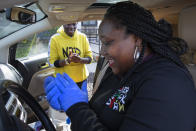 In this March 29, 2020, photo, volunteers Regina Summers, left, and Tonisha Wallace, use hand sanitizer between donated food deliveries in southeast Washington. Neighborhood deliveries are part of a new Martha's Table initiative, along with community partners, to get needed food directly to the neighborhoods they serve. These local volunteers are the tip of the spear for a grassroots community effort to keep Washington's most vulnerable neighborhoods fed during the unprecedented coronavirus crisis which has nearly shut down the American economy. (AP Photo/Jacquelyn Martin)