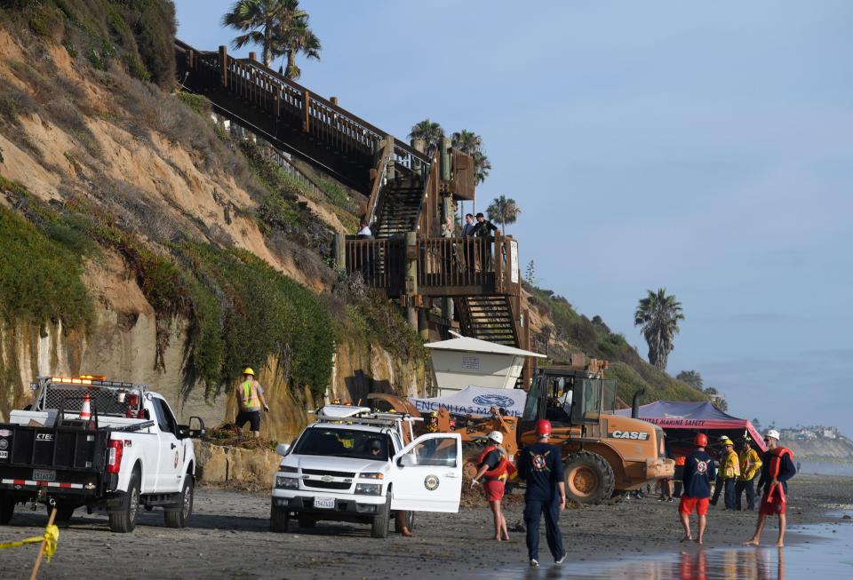 Lifeguards and search and rescue personnel work at the site of a cliff collapse at a popular beach Friday, Aug. 2, 2019, in Encinitas, Calif.