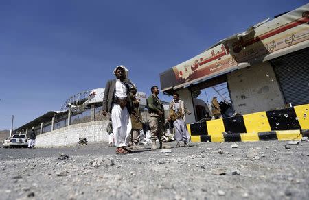 Houthi fighters stand next to damaged shops outside a Presidential Guards barracks on a mountain overlooking Presidential Palace in Sanaa January 20, 2015. REUTERS/Khaled Abdullah