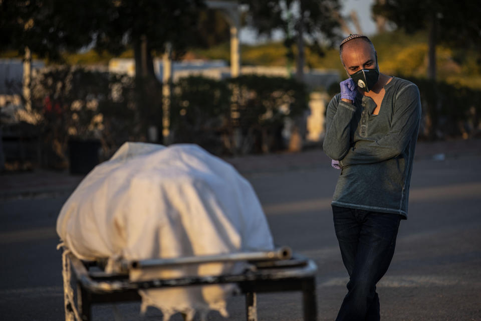 A relative attends a funeral of a Jewish man who died from coronavirus in the costal city of Ashkelon, Israel, Thursday, April 2, 2020. (AP Photo/Tsafrir Abayov)