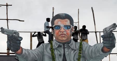 FILE PHOTO - Fans of south Indian film star Rajinikanth pour milk as an offering over his cut-out on the release date of his new movie "Endhiran" (Robot) in Chennai, India, October 1, 2010. REUTERS/Babu/File Photo