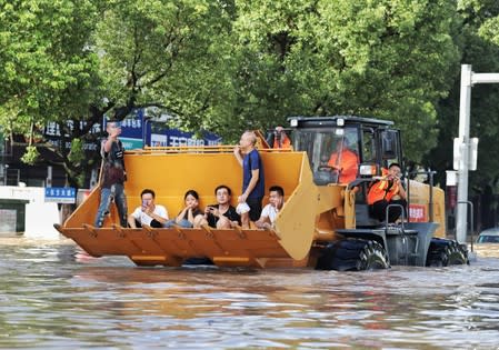 Rescue workers evacuate stranded residents with a bulldozer on a flooded street after typhoon Lekima hit Taizhou, Zhejiang