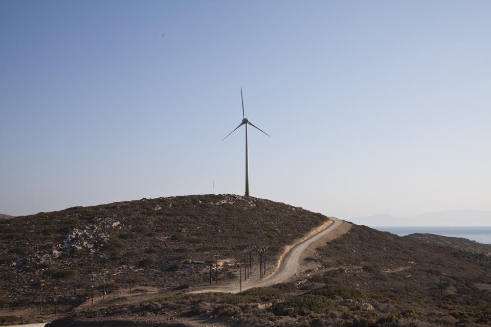 In this Thursday, Aug. 9, 2018, photo a road leads past a wind turbine stands on the Aegean island of Tilos, Greece. When the blades of the 800 kilowatt wind turbine start turning, Tilos will become the first island in the Mediterranean to run exclusively on wind and solar power, feeding the needs of its population of some 400 people in winter, and some 3000 in summer. (AP Photo/ Iliana Mier)