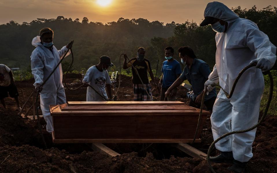 Grave diggers conduct a burial at Jatisari public cemetery, reserved for suspected COVID-19 victims on July 2, 2021 in Semarang, Central Java, Indonesia. Indonesia's President Joko Widodo announced on Thursday to place 'emergency restrictions' on Java and Bali islands from July 3 to 21, aiming to tame the recent COVID-19 surge. The country recorded more than 25,000 new infections and the 539 people reported dead on Friday. - Getty Images