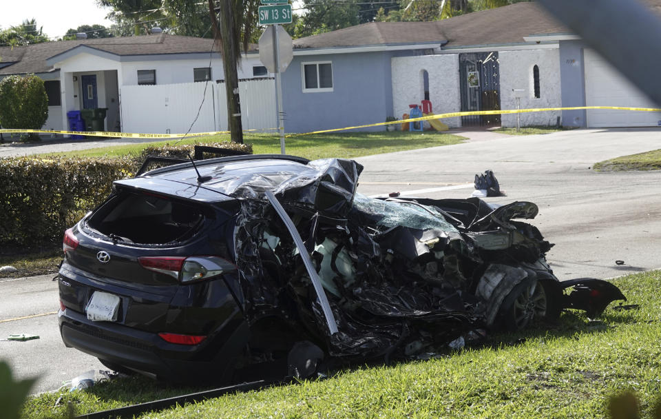 The SUV which was struck by an airplane Monday is seen behind police lines on a residential street near North Perry Airport in Pembroke Pines, Tuesday, March 16, 2021. A four-year-old child riding in the vehicle and the pilot and passenger in the plane were killed. (Joe Cavaretta/South Florida Sun-Sentinel via AP)