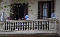 Varias personas se toman algo sentadas en el balcón de su casa de Barcelona. (Foto: Emilio Morenatti / AP).