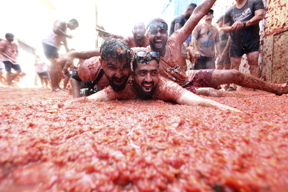 People react during the annual tomato fight fiesta called” Tomatina” in the village of Bunol near Valencia, Spain, Wednesday, Aug. 30, 2023. Thousands gather in this eastern Spanish town for the annual street tomato battle that leaves the streets and participants drenched in red pulp from 120,000 kilos of tomatoes. (AP Photo/Alberto Saiz)