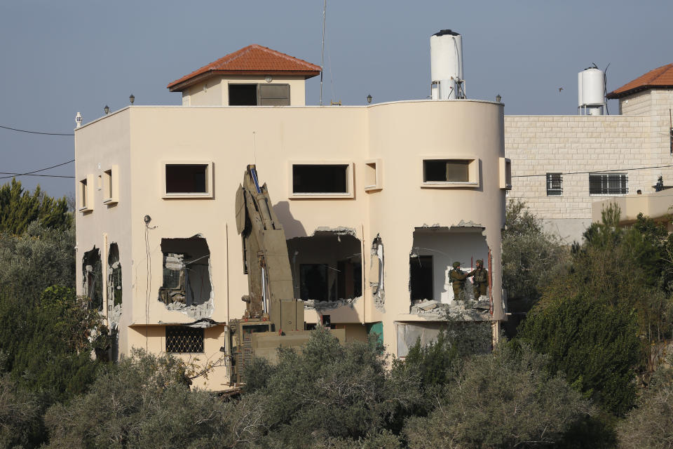 Israeli soldiers stand on the balcony of a partially demolished house in the village of Shweikeh, near the West Bank city of Tulkarem, Monday, Dec. 17, 2018. The Israeli military has partially demolished the home of Ashraf Naalweh, a Palestinian accused of killing two Israelis in a West Bank attack two months ago. (AP Photo/Majdi Mohammed)