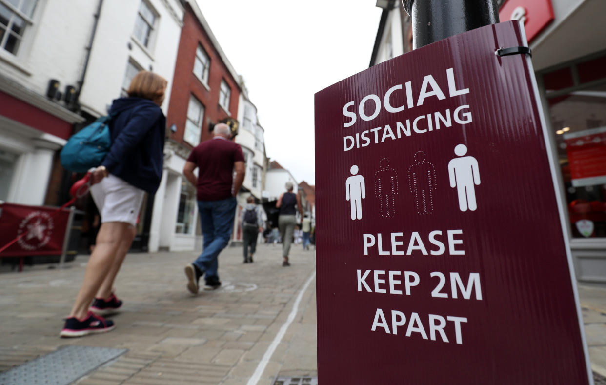 People make their way past a social distancing sign on the High street in Winchester, Hampshire, after the lifting of further coronavirus lockdown restrictions in England. (Photo by Andrew Matthews/PA Images via Getty Images)