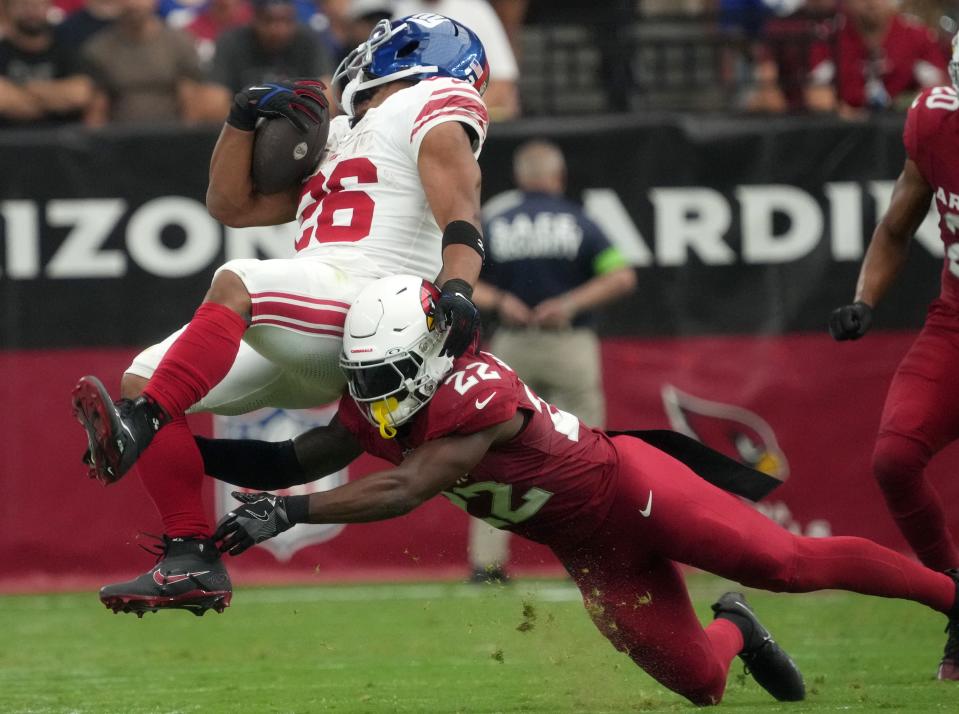 Arizona Cardinals safety K'Von Wallace (22) tackles New York Giants running back Saquon Barkley (26) at State Farm Stadium in Glendale on Sept. 17, 2023.