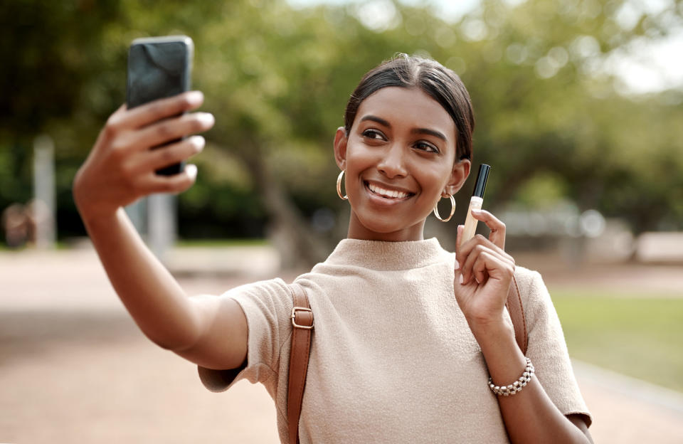 An influencer taking a selfie while holding a product