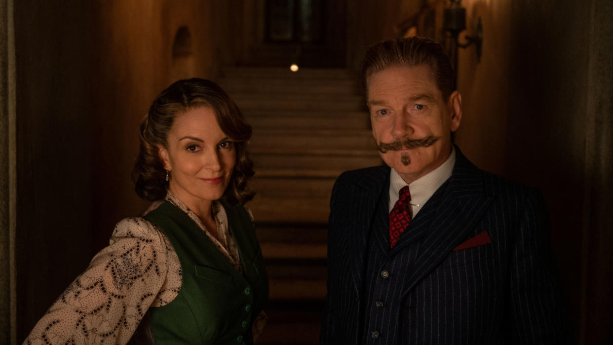  Tina Fey and Kenneth Branagh pose for a photo in a corridor lit by torches in A Haunting in Venice. 