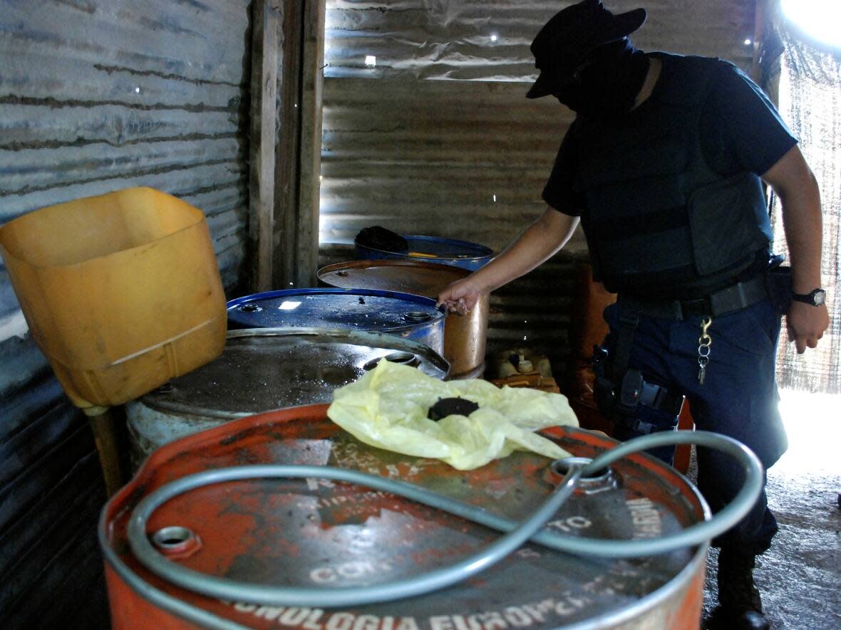 In this 2011 file photo, a Mexican police officer inspects barrels containing stolen diesel fuel in the municipality of Apodaca. The former head of security for Mexico's state oil monopoly Pemex is currently facing extradition from Canada on charges of covering up a fuel theft racket. (Josue Gonzalez/Reuters - image credit)