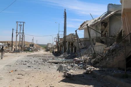 A man walks near damaged houses after Syrian rebels and the al Qaeda-affiliated Nusra Front took control of al-'Iss town, in Aleppo countryside, Syria April 2, 2016. REUTERS/Ammar Abdullah