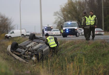 A Surete du Quebec (SQ) officer investigates an overturned vehicle in Saint-Jean-sur-Richelieu, Quebec October 20, 2014. REUTERS/Christinne Muschi